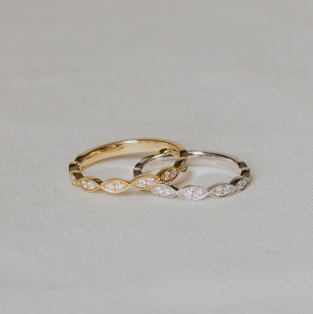 Two gold rings with diamond accents on a light gray background