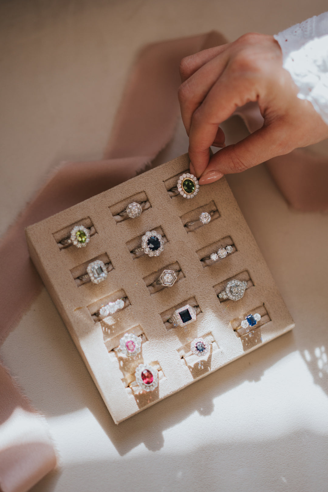 Set of rings displayed in a box with a hand reaching for one of them.